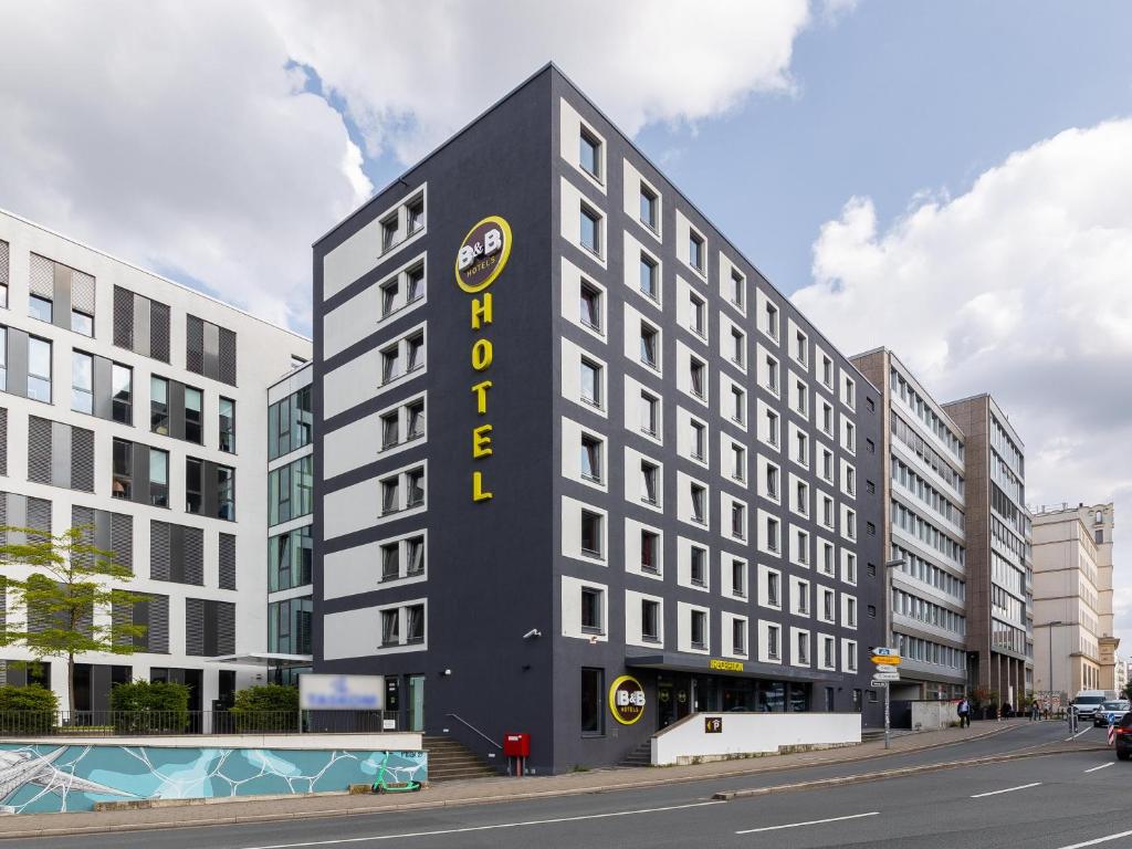 デュッセルドルフにあるB＆B ホテル デュッセルドルフ シティの黄色の看板が貼られた高い黒い建物
