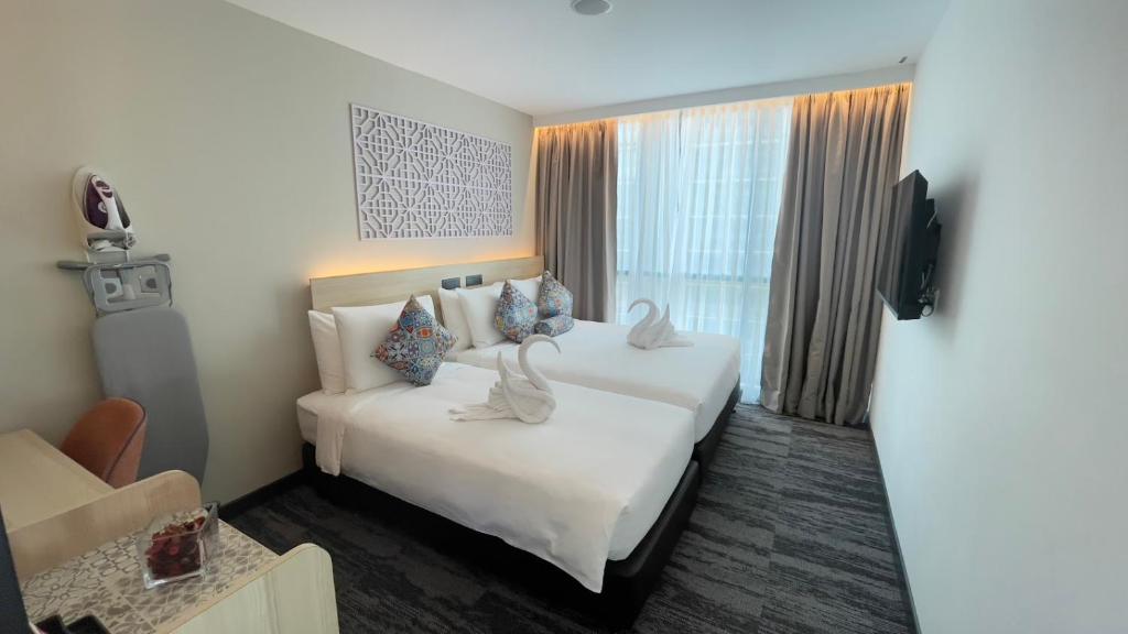 A twin-bed room with a curtained window, compact desk and ironing station.