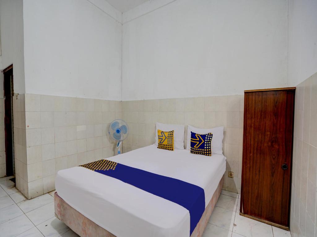 Schlafzimmer mit einem Bett mit blauen und gelben Kissen in der Unterkunft SPOT ON 92876 Homestay Kedamean in Gresik