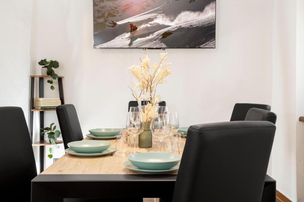 una mesa de comedor con sillas y una mesa con platos y vasos. en HelloChalet - Le Fleury Family Apartment 600mt cablecar, en Valtournenche