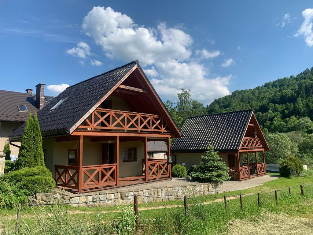 uma casa com um telhado de gambrel com um quintal em Domki nad Dunajcem em Tylmanowa