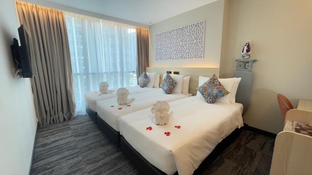A twin room with two decorated beds, a full-height window and a small work table.