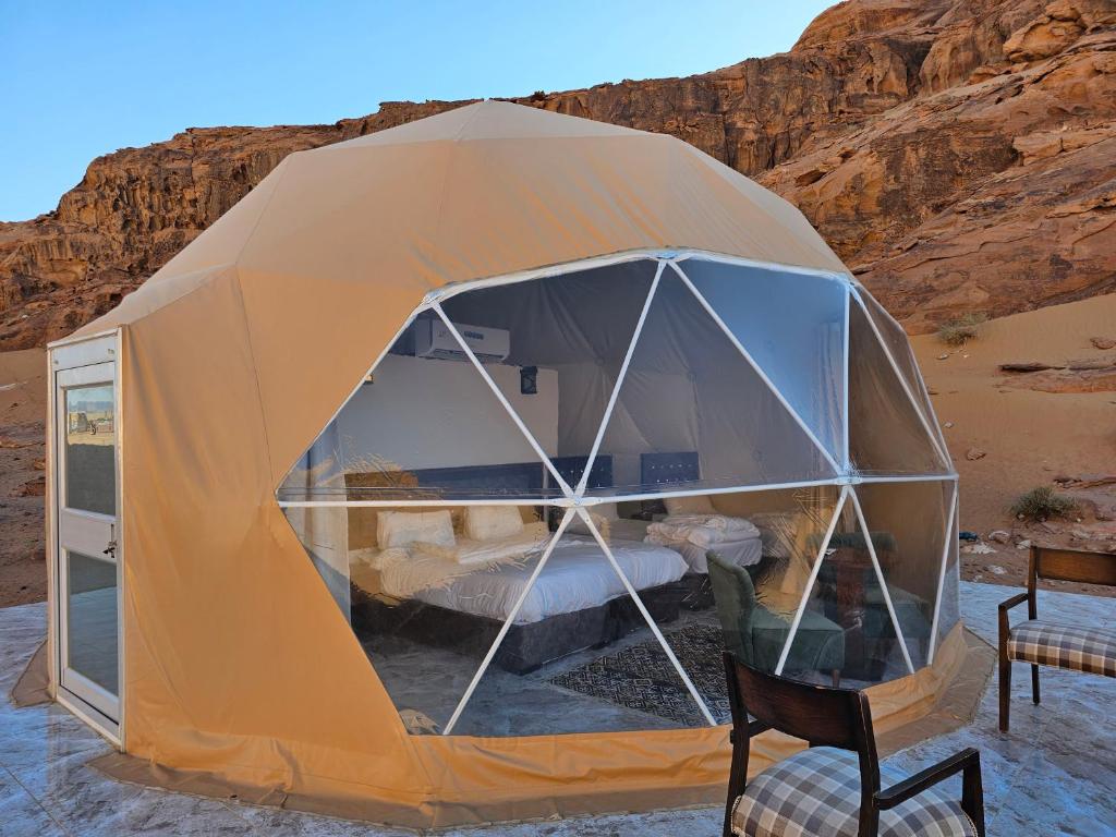 a tent in the desert with a chair at Mouna Luxury Rum Camp in Wadi Rum