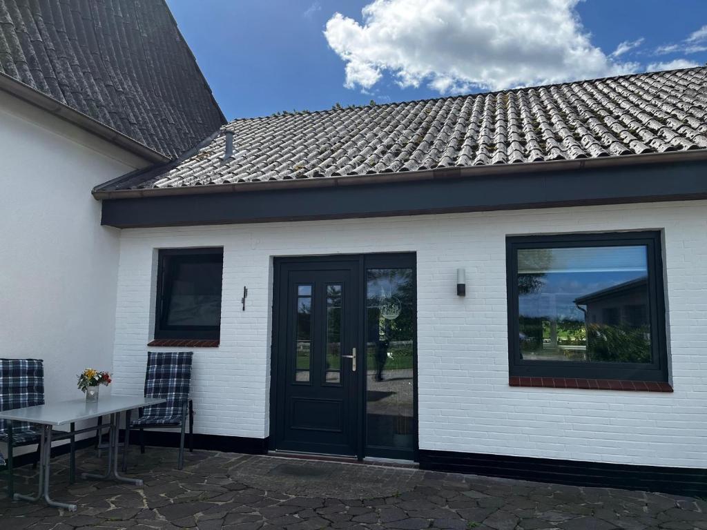 a white house with a black door and a table at Ferienwohnung Lüttje Glück in Böxlund