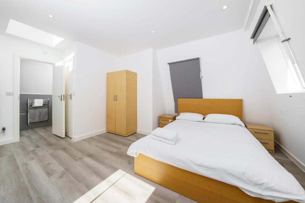 a bedroom with a large bed with white sheets at Modern Apartment in South West London in London