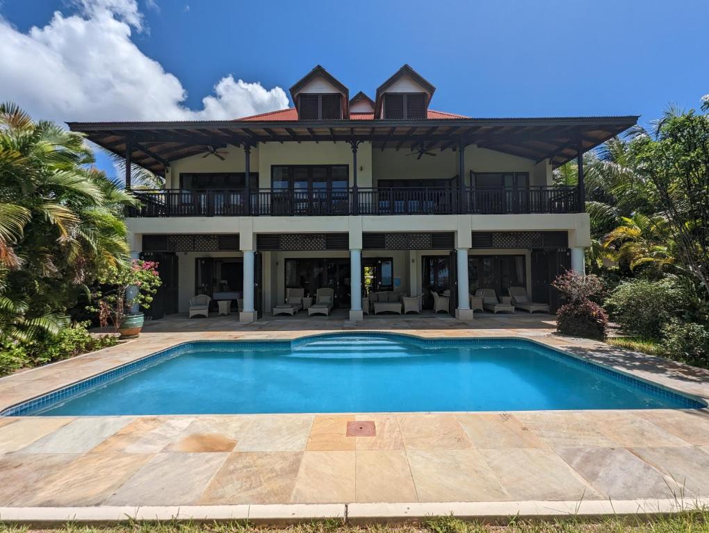 a large house with a swimming pool in front of it at Villa Magnifique by Simply-Seychelles in Eden Island