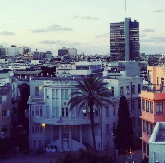 a white building with a palm tree in a city at Studio avec roof top, vue d'exception, 5mn mer. in Tel Aviv