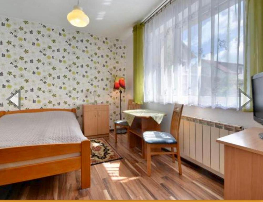 a bedroom with a bed and a table and a television at Willa Dominik 2 in Jastarnia