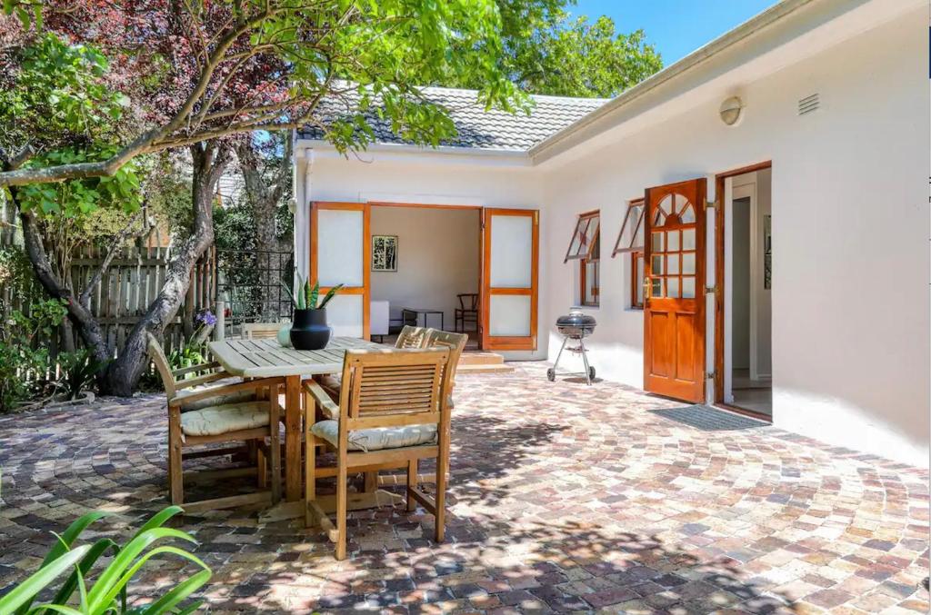 a patio with a table and chairs and a house at Constantia Oasis Petite in Cape Town