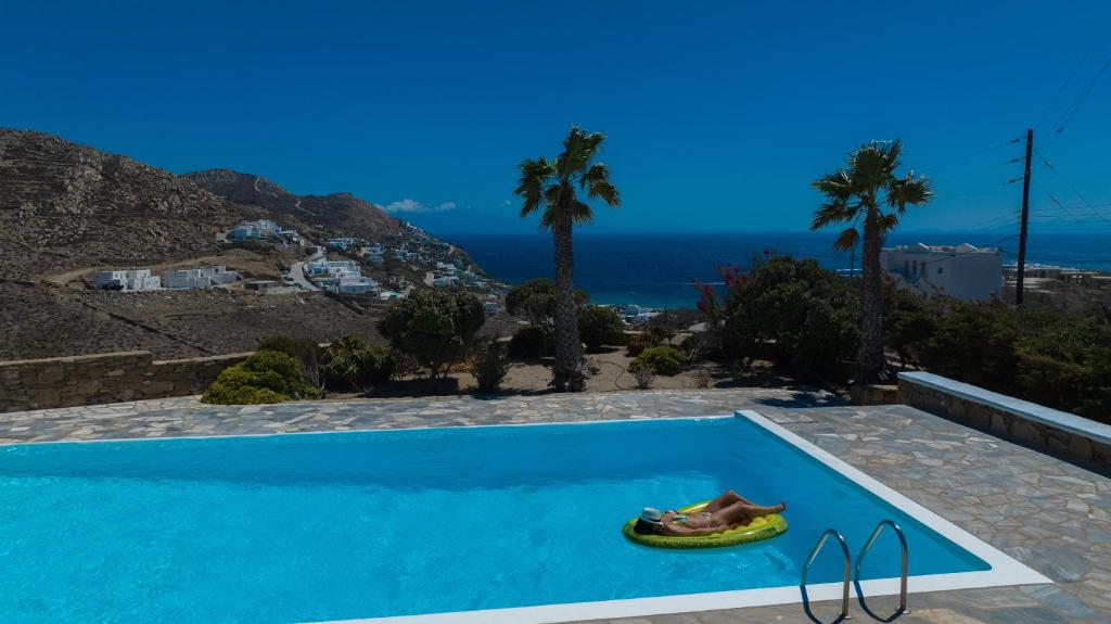 a person laying on a swimming pool with the ocean in the background at VILLA 11.7 in Elia Beach