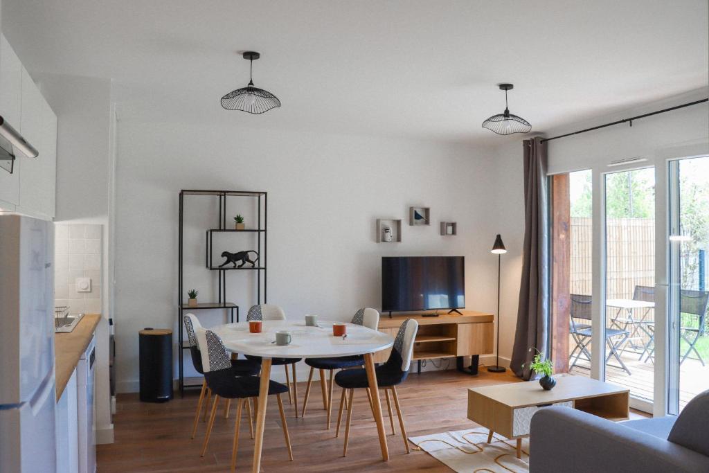 een woonkamer met een witte tafel en stoelen bij Appartement élégant et bien situé in Biscarrosse