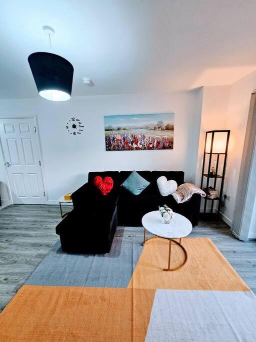 a living room with a black couch and a table at Swanky 1-Bedroom Apt in Walsall in Bescot