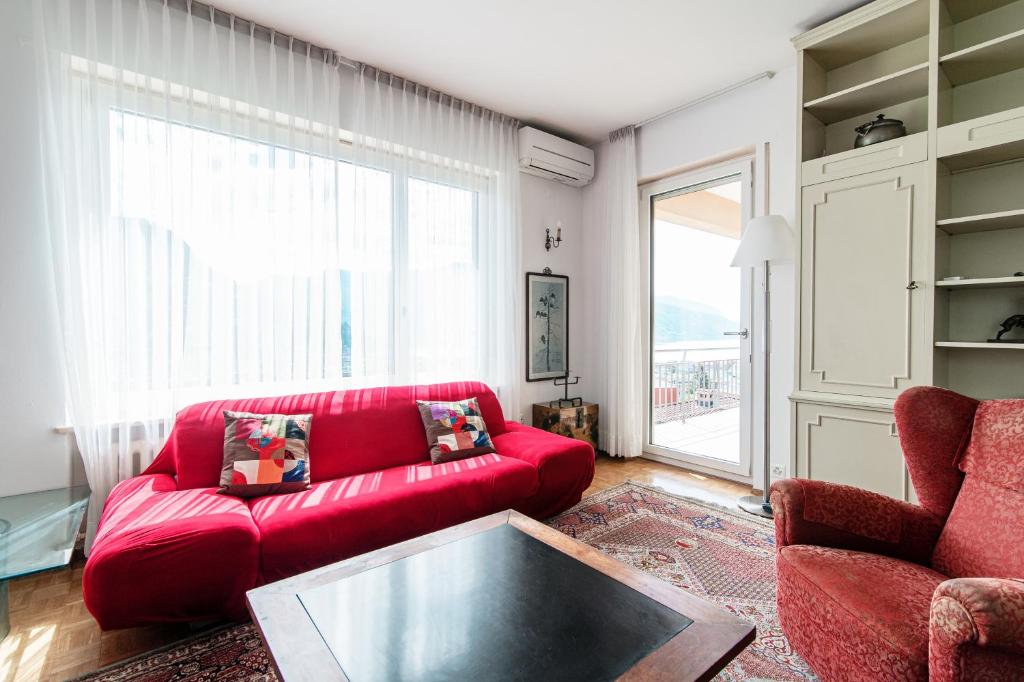 un soggiorno con divano rosso e tavolo di Miravalle Lakeview by Quokka 360 - large windows and magical views a Massagno