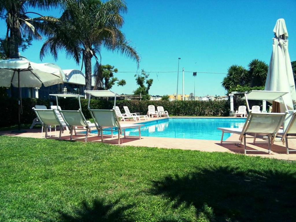 eine Gruppe von Stühlen neben einem Pool in der Unterkunft Solemare Residence in Donnalucata