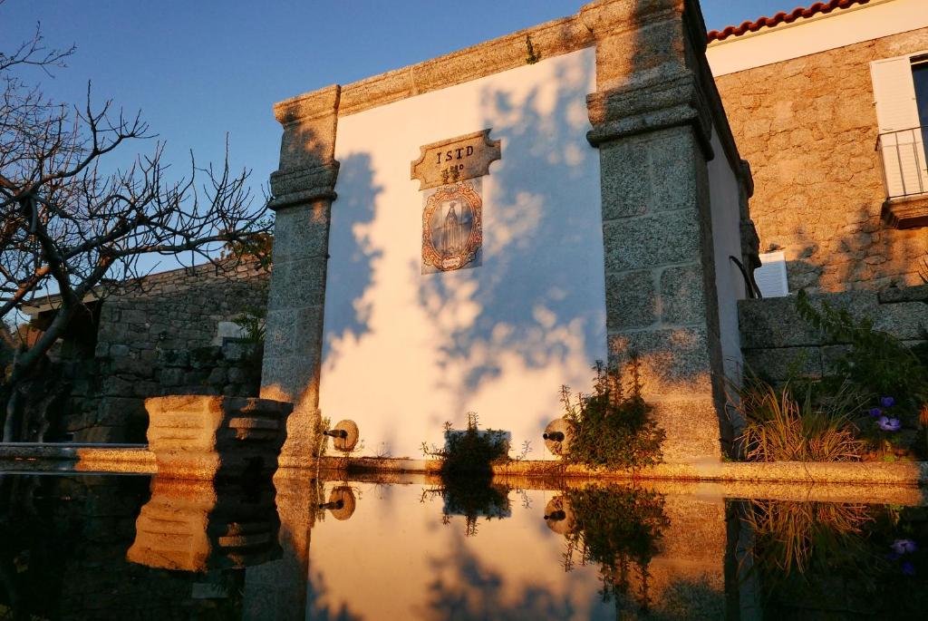 un reflet d'un bâtiment dans un bassin d'eau dans l'établissement Casa do Meio em Quinta de São Pedro de Vir-a-Corça, à Monsanto