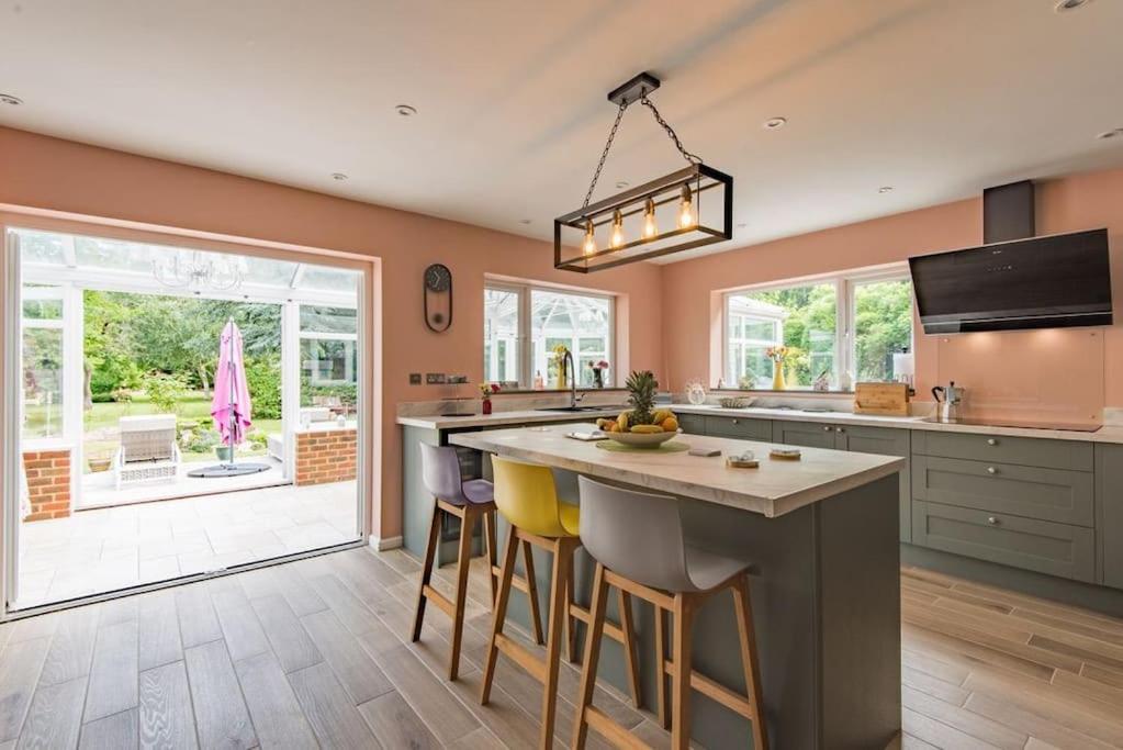a kitchen with a large island with bar stools at Sycamores - Fabulous family home with huge garden in Kent