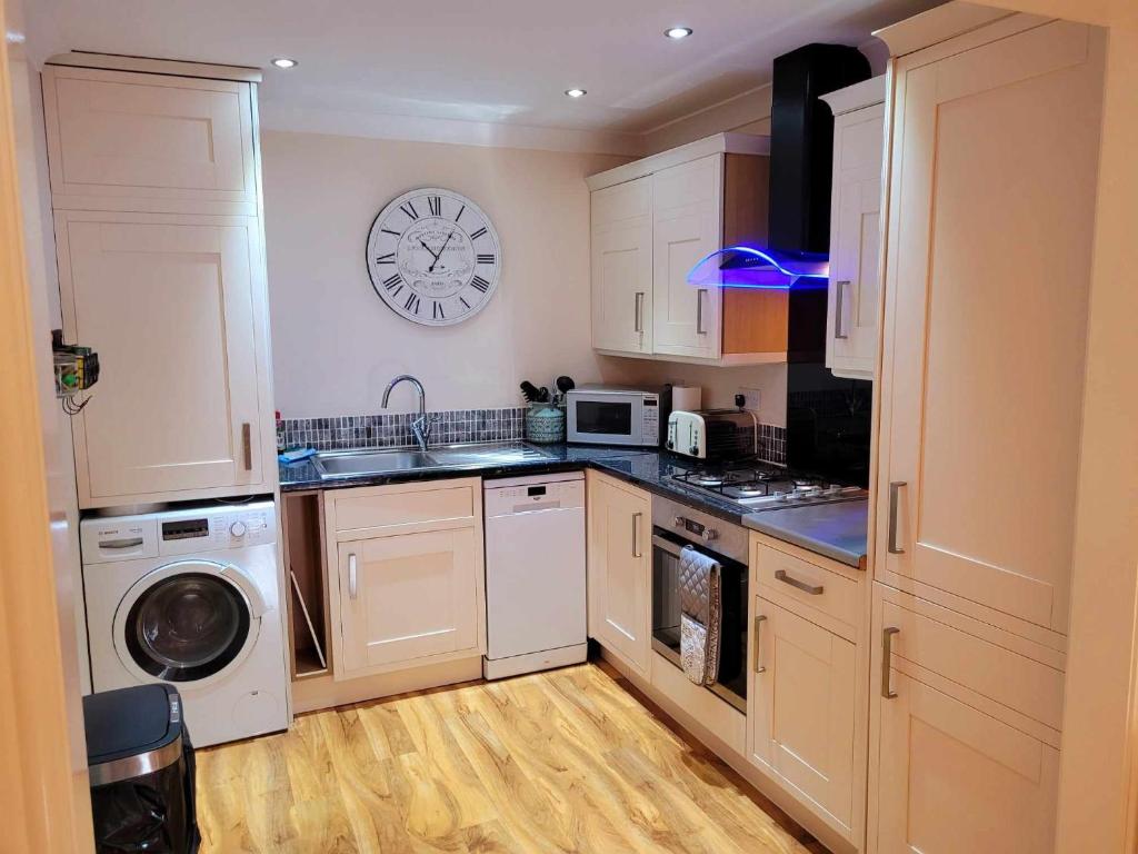 a kitchen with white cabinets and a clock on the wall at Apartment 3 in Darlington