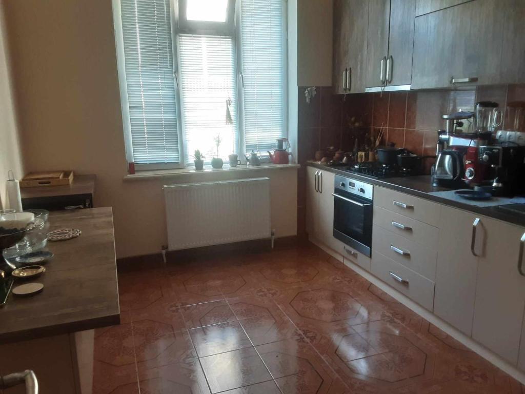 a kitchen with wooden cabinets and a tile floor at Colchis ca777 in Kutaisi