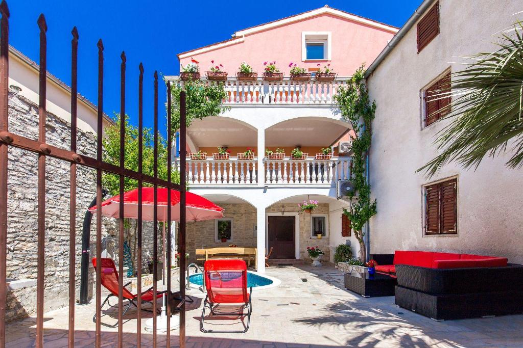 a house with a balcony with chairs and an umbrella at Ferienwohnung nur 700 Meter bis zum Sandstrand mit Pool, Küche, Bad, Balkon, BBQ in Medulin