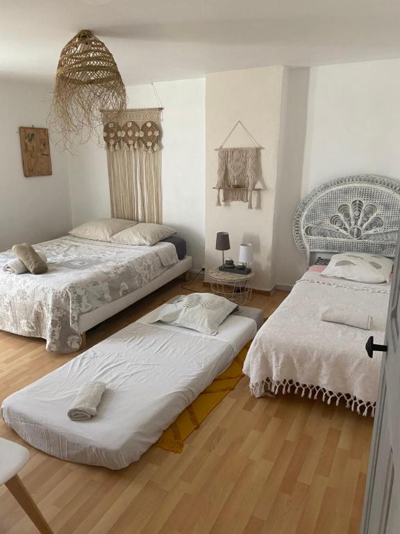 2 camas en una habitación con suelo de madera en Chez Berthe, en Arles