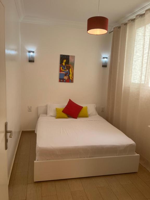 - une chambre dotée d'un lit blanc avec des oreillers jaunes et rouges dans l'établissement Well being point, à Agadir