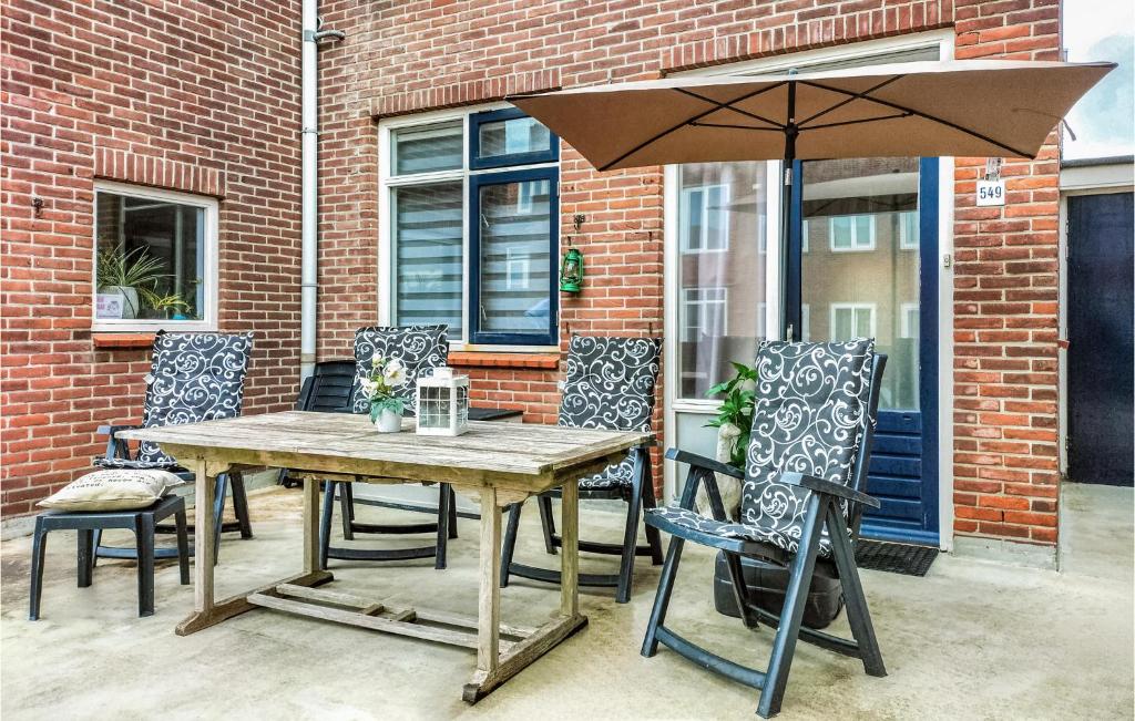 a wooden table and chairs with an umbrella at 3 Bedroom Stunning Home In Vlissingen in Vlissingen