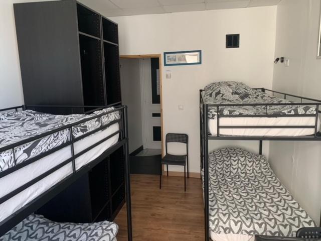 two bunk beds in a room with a chair at Hôtel Le National in Saint-Étienne