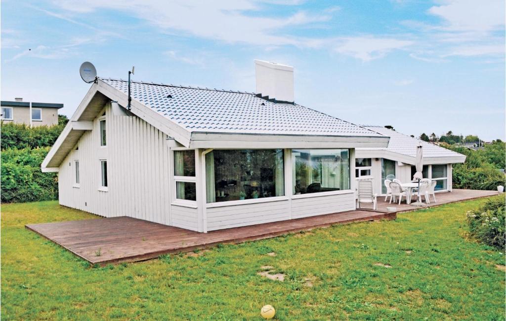 a small white house with a large deck at Cozy Home In Ebeltoft With Sauna in Ebeltoft