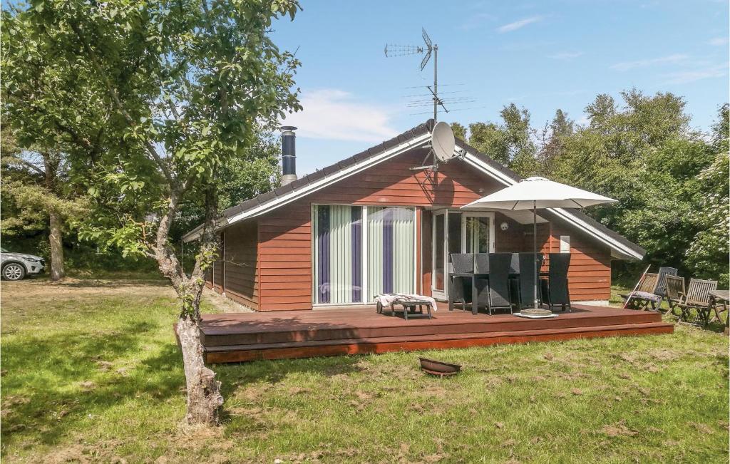 a small house with a deck and an umbrella at Cozy Home In Grenaa With Wifi in Stokkebro