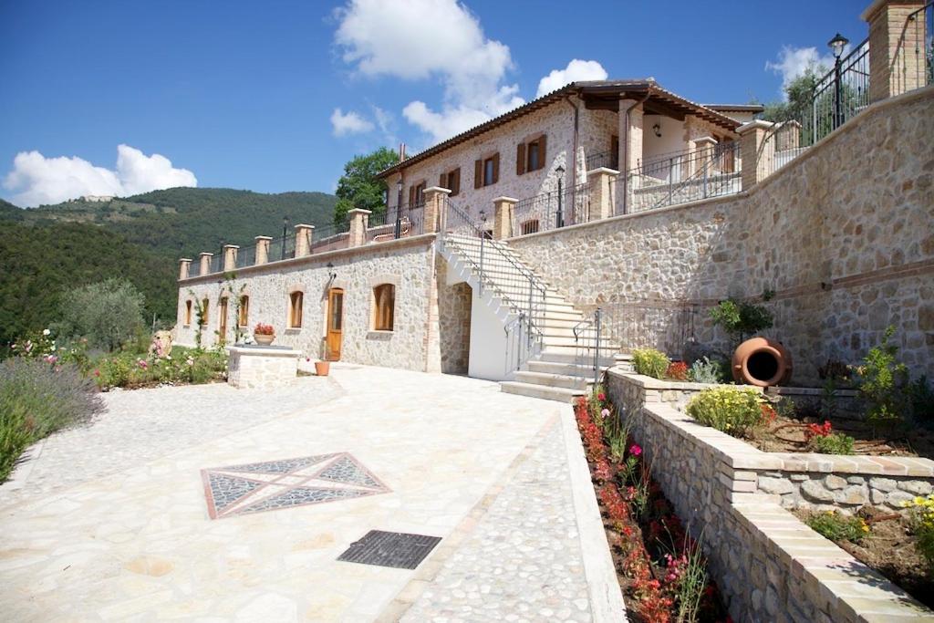 a large stone building with a staircase and a courtyard at Pucci Country House in Ferentillo