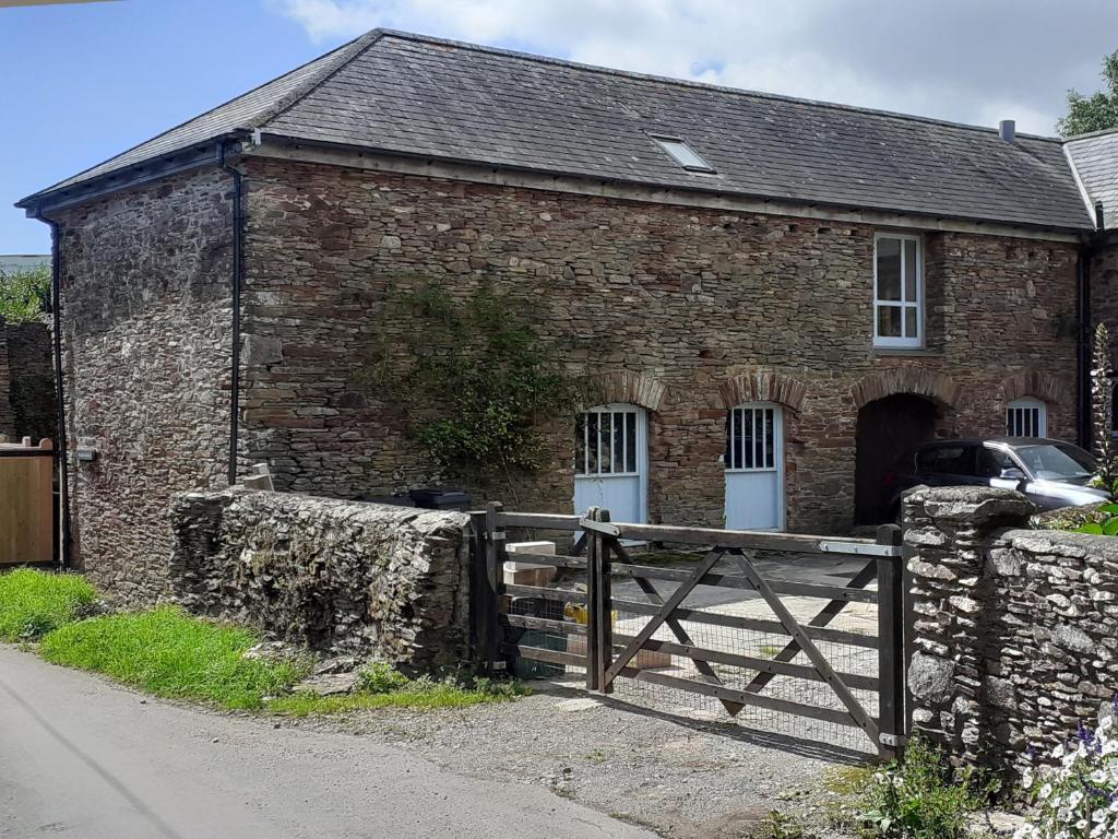 an old brick building with a wooden gate in front of it at Swallows Barn in Totnes