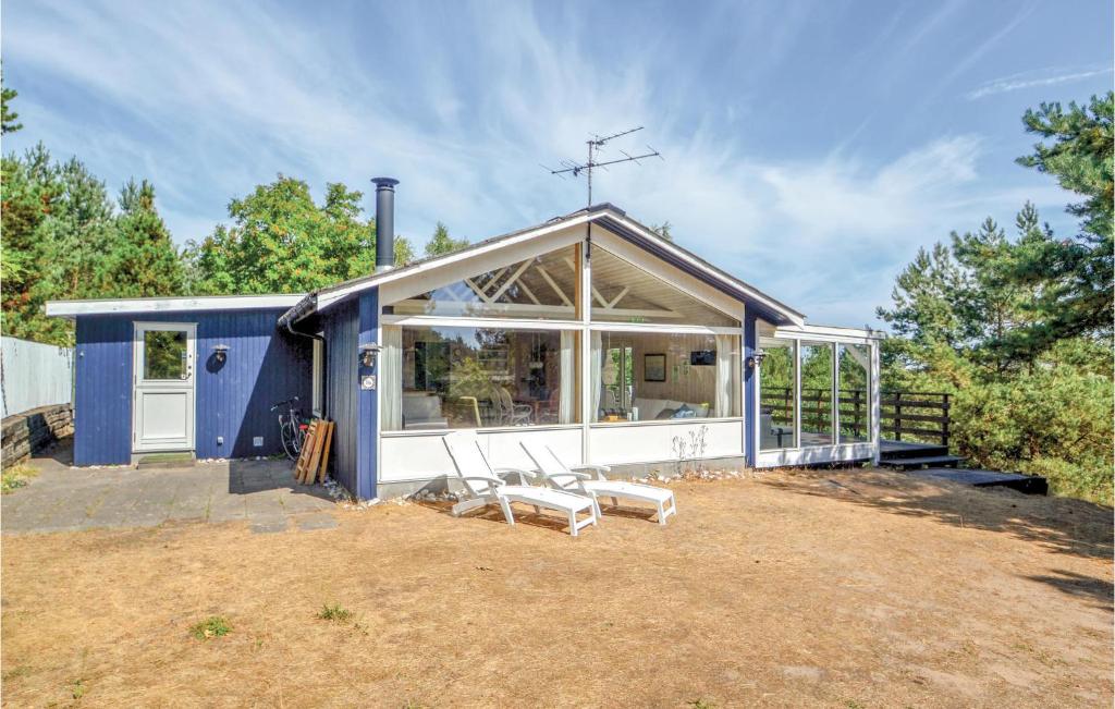 ein blaues Haus mit zwei weißen Stühlen davor in der Unterkunft Stunning Home In Ebeltoft With Wifi in Ebeltoft