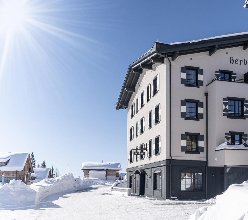 a building in the snow with the sun behind it at HERBERT - Boutique Apartments inkl Lungau Card in Katschberghöhe