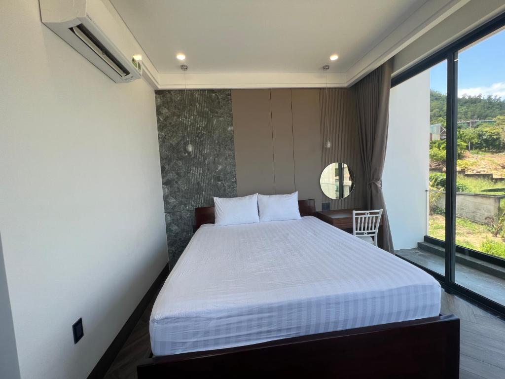 ein Schlafzimmer mit einem Bett und einem großen Fenster in der Unterkunft Nancy Grand Tran Group Villa 1 in Vũng Tàu