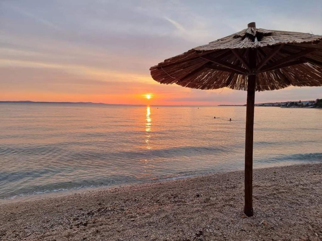 een parasol op het strand met de zonsondergang bij Rise of Olympus apartmani in Zadar