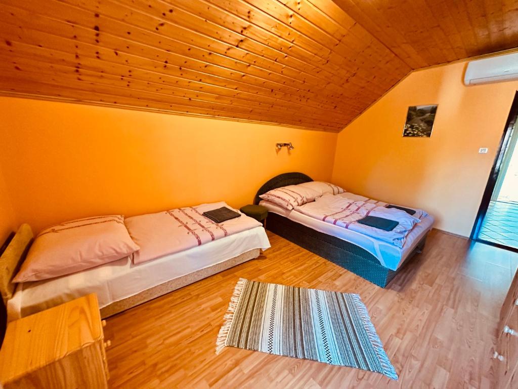 two beds in a room with orange walls and wooden floors at Emília Apartment in Balatonföldvár