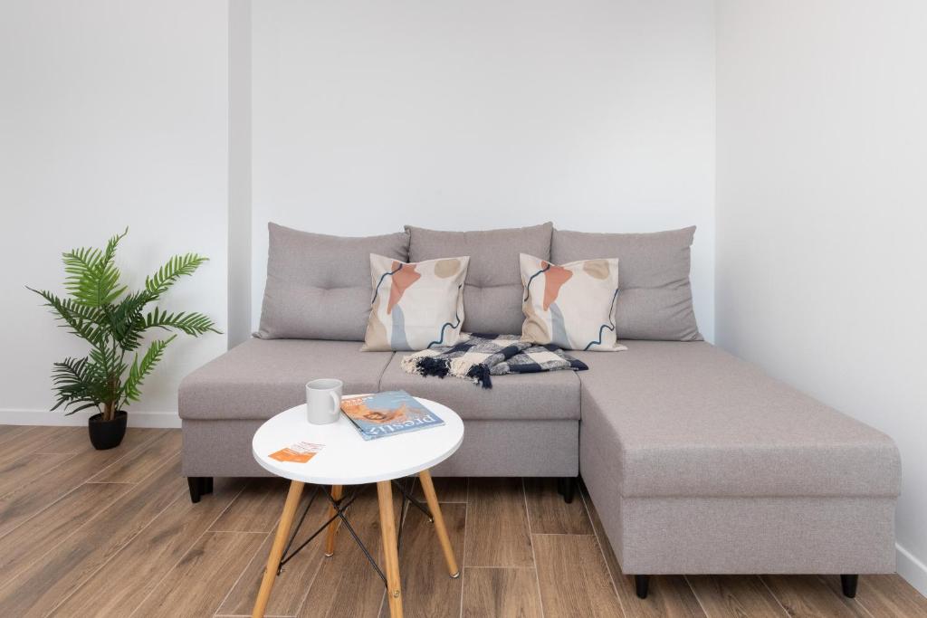 a couch with pillows and a table in a living room at Apartment Park de Gaulle Gdansk Wrzeszcz by Renters in Gdańsk