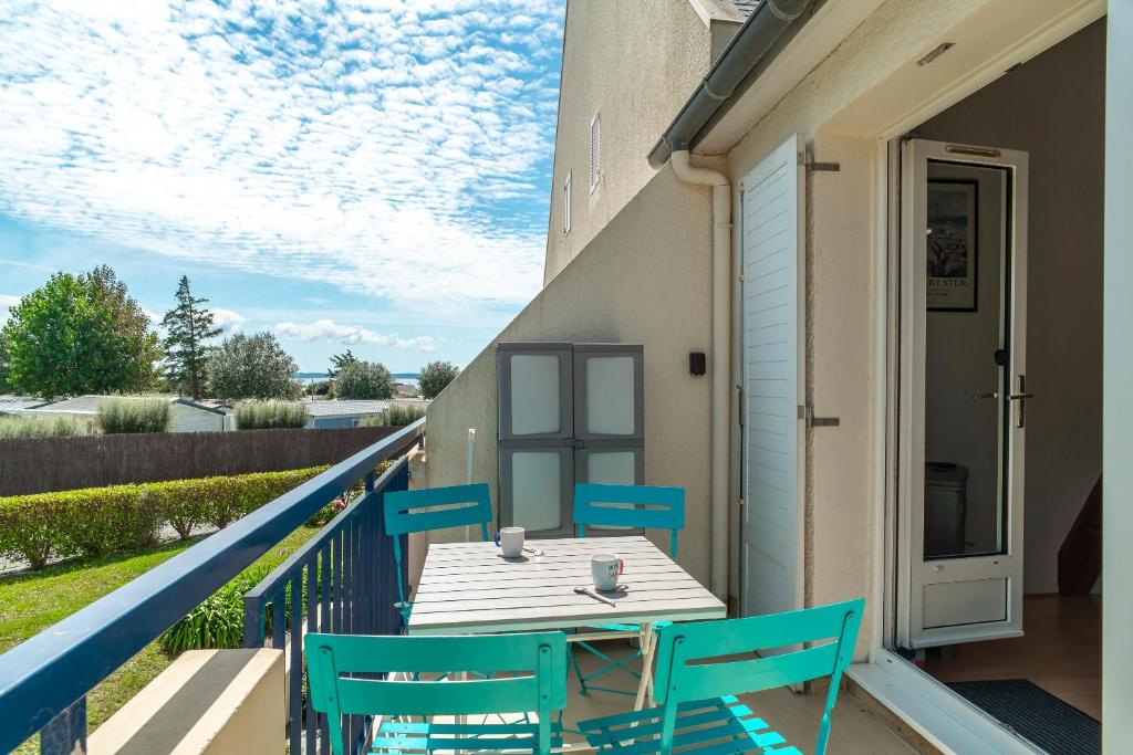 a patio with a table and chairs on a balcony at Glazik - Appartement à 5 min de la plage in Saint-Nic