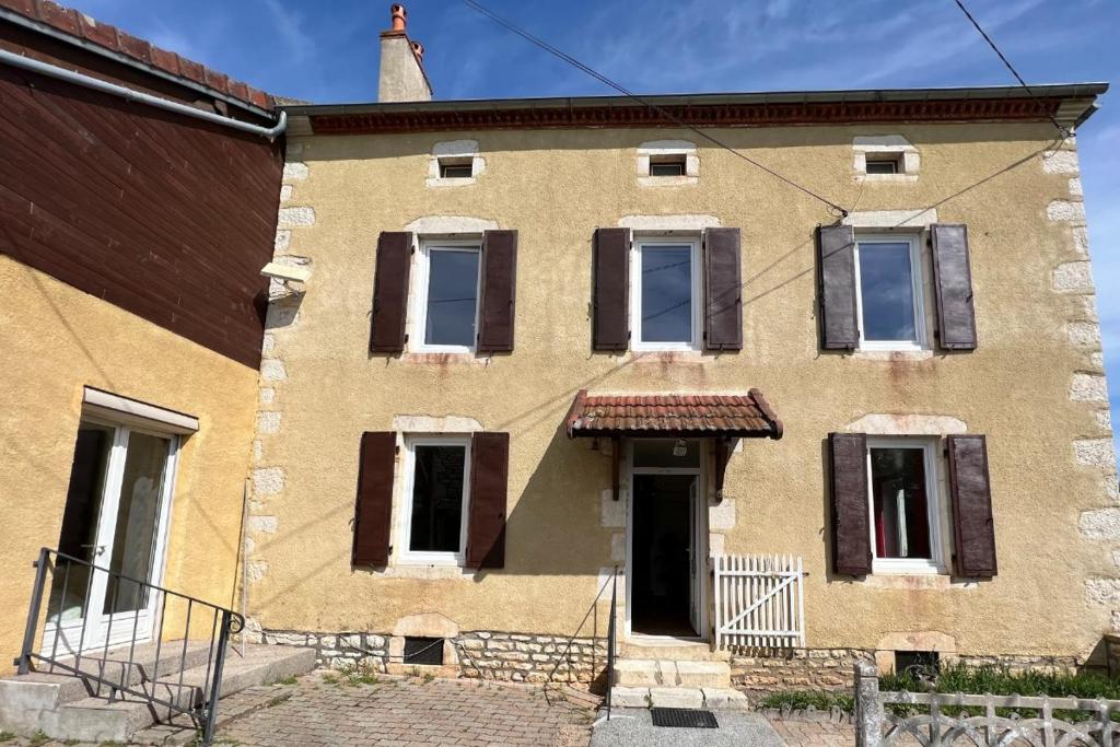 un antiguo edificio de ladrillo con ventanas y una puerta en Les Gites de Louisette 1886 en Ébreuil