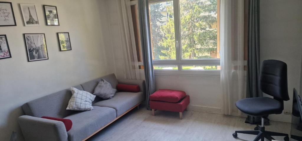 sala de estar con sofá, silla y ventana en Confortable apartment self check in, en Savigny-sur-Orge
