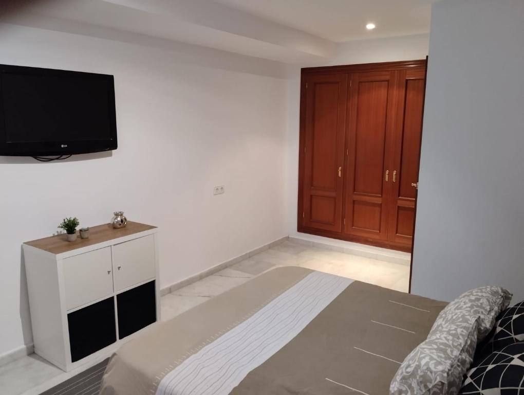 1 dormitorio con 1 cama y TV en la pared en Villa Lago Golf, 300m construidos en Jerez de la Frontera