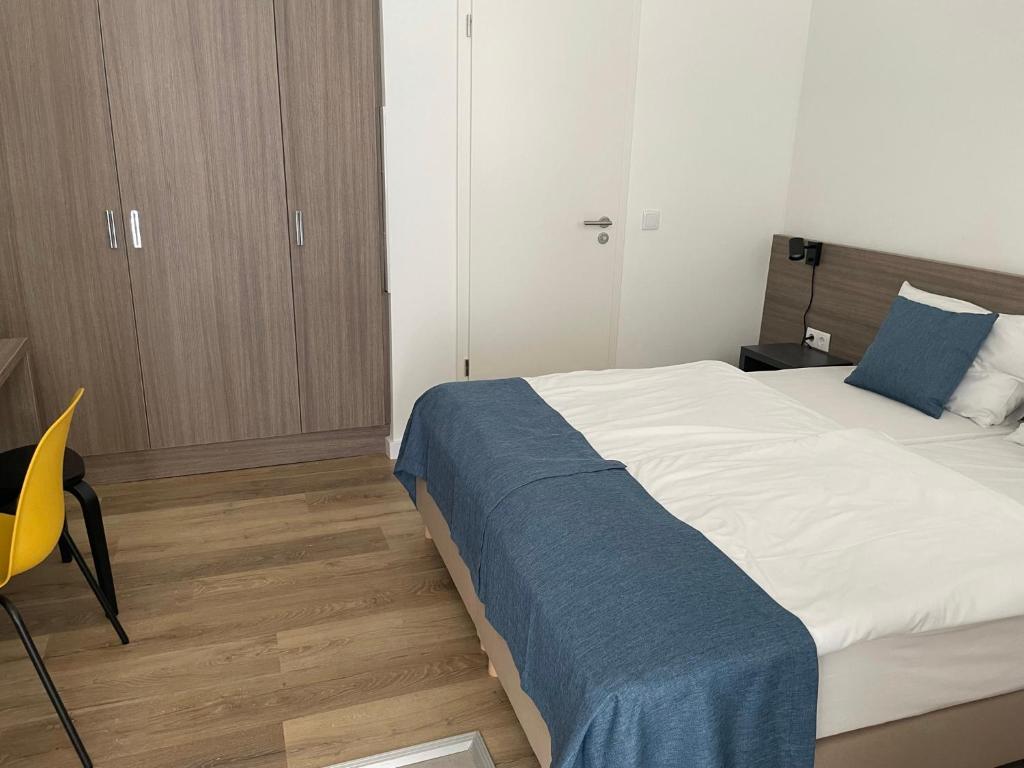 a bedroom with a large bed and a yellow chair at RES City Residence Hotel Budapest in Budapest