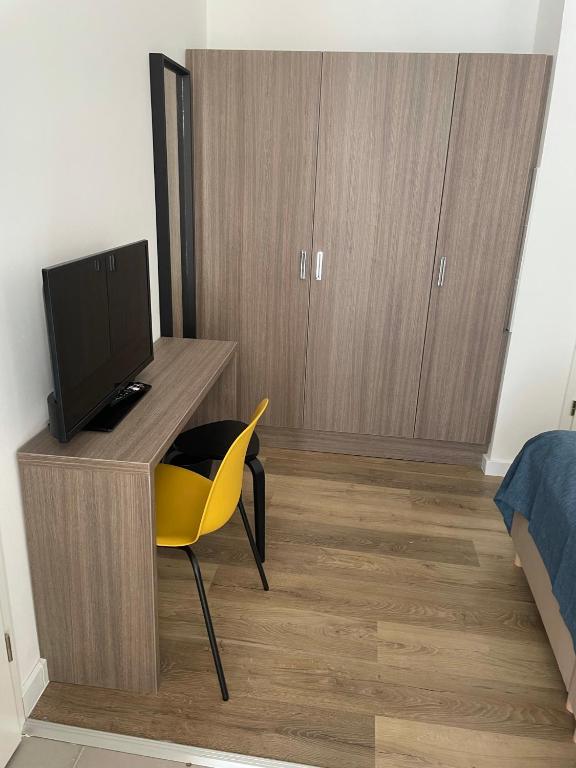 a bedroom with a desk with a tv and a yellow chair at RES City Residence Hotel Budapest in Budapest