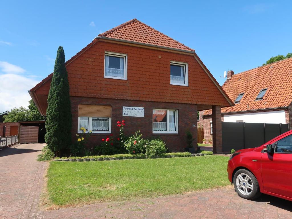 a red car parked in front of a house at Pension Seehund in Norden