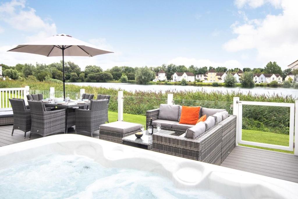 a deck with a hot tub and a table and chairs at Windrush Lake 65, Sunset Lodge - P in South Cerney