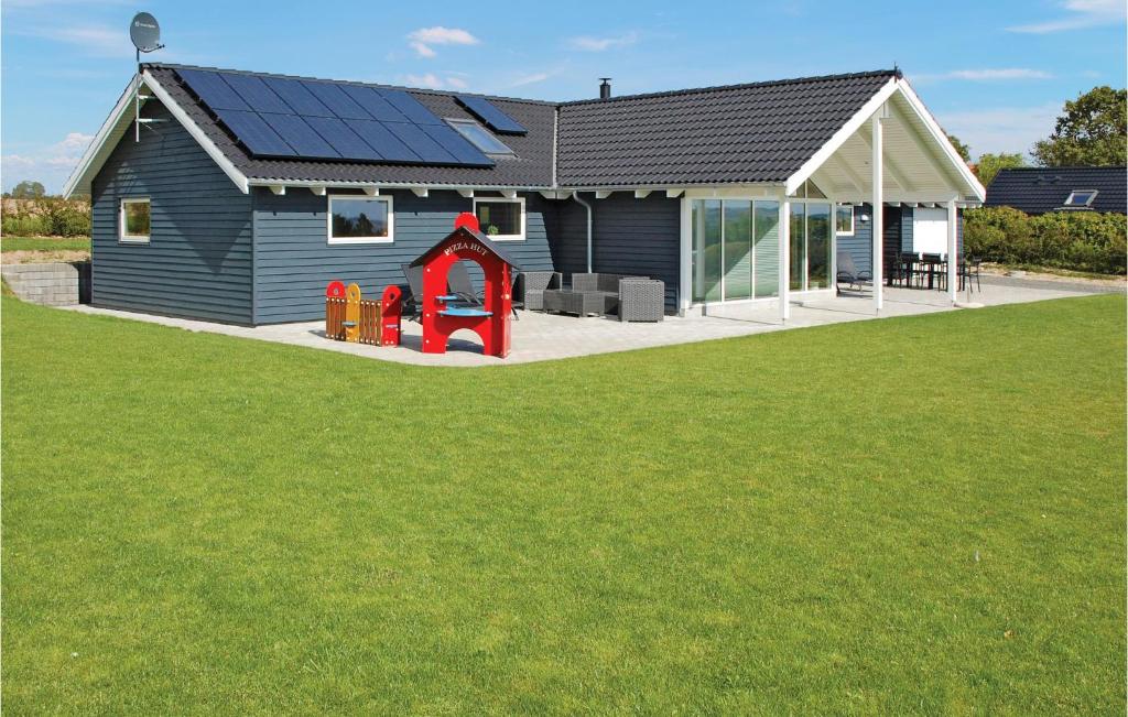 a house with solar panels on the roof and a playground at 4 Bedroom Awesome Home In Rnde in Rønde