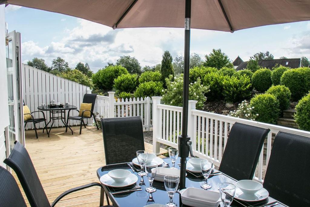 a patio with a table and chairs and an umbrella at Isis Lakes 09, ArtHouse in South Cerney