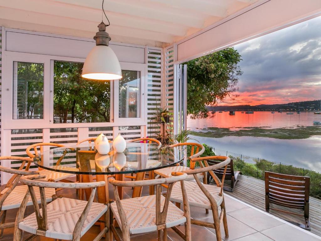 a dining room with a table and chairs and a view of the water at Sunset Lane Fairmile Point in Knysna