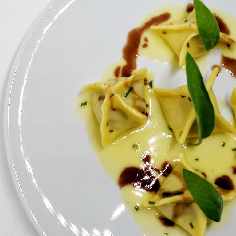 a plate of pasta with sauce and green leaves at Hotel Mirasole International in Gaeta