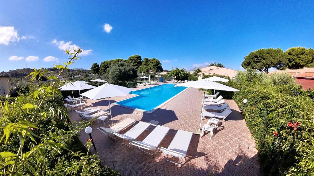 una piscina al aire libre con tumbonas y sombrillas en Villa Teti - Sicilia, en Campofelice di Roccella